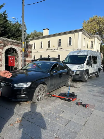Gündüz kaldırım kenarında sedan aracın ön lastiğinin sökülmesi