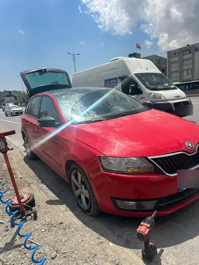 Yol kenarında kırmızı hatchback aracın ön lastiğine müdahale