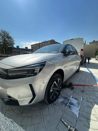 Gündüz otoparkta beyaz hatchback aracın ön lastiğinin krikoyla kaldırılması