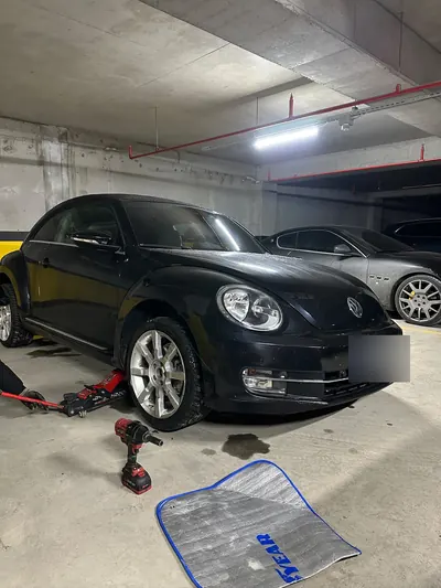 Kapalı otoparkta aracın ön lastiğinin krikoyla kaldırılıp değiştirilmesi